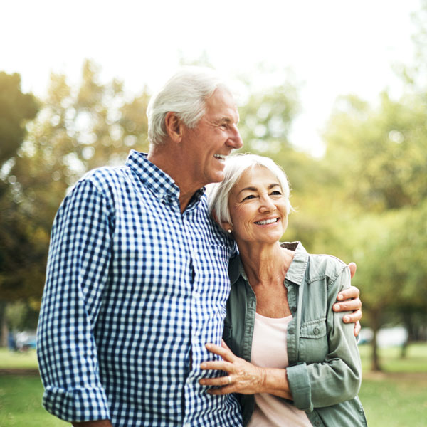 An older couple enjoying a sunny day in a park close together and smiling in Flagstaff, AZ