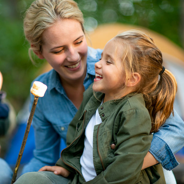 adult woman and daughter making smores