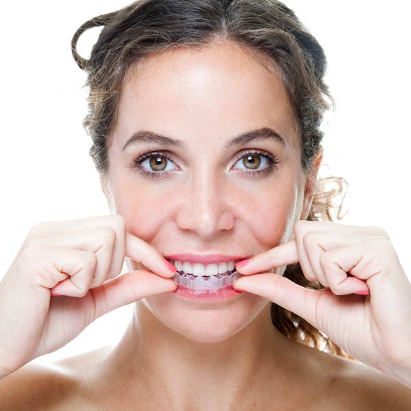 A woman grips her teeth with her hands, showcasing her clear aligners in Flagstaff and Cottonwood, AZ